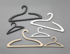  A selection of six modern clothes hangers designed by Dögg Design (Dögg Guðmundsdóttir), titled "Cygnet Hangers", in CNC-milled and color-lacquered plywood, displayed against a gray background, with two natural plywood-colored, two black, and two white hangers.