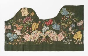  A dark green embroidered fabric fragment with an irregular top edge, featuring a symmetrical pattern of swirling paisley-like motifs in the center surrounded by a variety of colorful flowers and foliage in an ornate design.