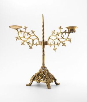  "Kandelaber by an unidentified artist, an ornate brass candelabra with a gilded foot and intricate openwork relief decoration. The piece possesses multiple arms for holding candles, detailed with scrollwork and floral patterns, set against a plain white background."