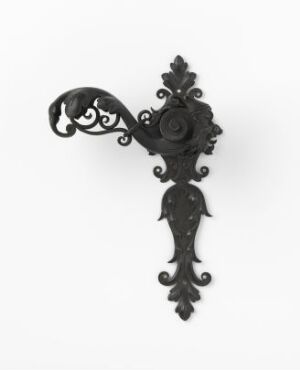  An ornate, dark-colored metal wall bracket with a central rosette and intricate scrollwork, set against a light background, highlighting its decorative craftsmanship and vintage style.