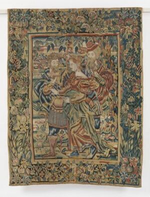  A photograph of a historical tapestry with a detailed floral background and human figures in medieval or renaissance attire. The border of the tapestry is ornate with a variety of colors including red, green, blue, brown, and gold, showcasing a high level of textile craftsmanship.