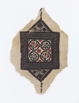  An irregularly shaped piece of beige textile with a central square of dark brown or black fabric adorned with red floral embroidery and intricate geometric designs, suggesting a handcrafted traditional artwork.