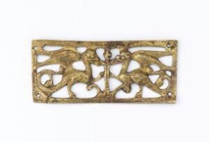  A rectangular gilded copper-based metal object with intricate openwork relief decoration featuring symmetrical swirls and organic shapes, created by an unidentified artist and known as "Beslag."