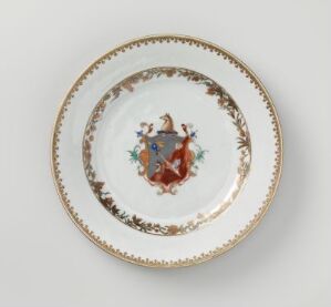  An ornate porcelain plate with a central coat of arms in terracotta red and blue, surrounded by a gold ring and an intricate brown, green, blue, and gold leafy pattern on the rim.