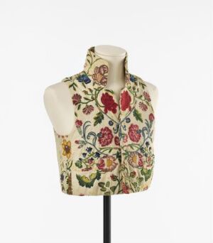  A mannequin torso displays an elaborate embroidered waistcoat with a floral pattern featuring red, pink, yellow, blue, and purple flowers on a beige background, set against a light grey or white backdrop.