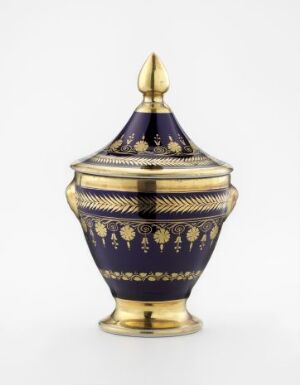  A rich cobalt blue and gold ornate vessel with a pine cone-like motif around the middle, gold bands, a flared golden base, and a pointed finial atop the lid, radiating a sense of luxury and fine craftsmanship. Artist name and title unknown.