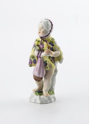  A porcelain figurine of an elderly woman with a white bonnet adorned with blue floral patterns, wearing a yellowish-olive floral jacket with light purple accents, holding a matching purple pouch and a closed fan, all against a plain white background. Artist name and title are unknown.