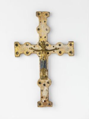  A gilded wood crucifix titled "Krusefiks" with cast and gilded copper elements, featuring intricate carvings and champlevé enamel, crafted by an unidentified artist. The cross shows a rich golden color with spots of bright enamel, likely embellishing the already profound religious symbolism of the object.