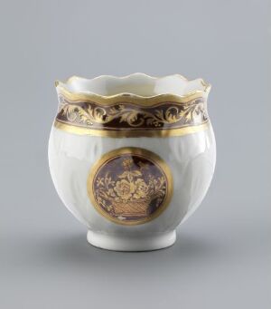  A small ornamental white porcelain sugar bowl with a scalloped edge, gilded detailing, and a central medallion with a dark background and gold design, set against a light grey backdrop.