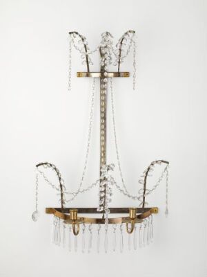  An elegant chandelier with a vertical structure and three sets of curved arms, adorned with strings of clear faceted crystal droplets and golden metalwork, against a creamy white background. Artist name and title are unknown.