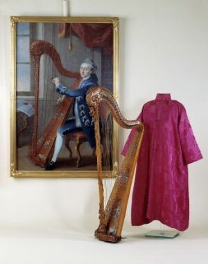  An elegant, long-sleeve, ankle-length robe in a vibrant pinkish-red with a subtle floral damask pattern on display on a mannequin against a light background. Artist name and title are unknown.