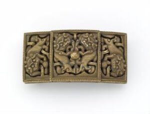  A small, foldable triptych panel with intricate, symmetrical, raised designs in a golden-brown metal, possibly bronze, with a central emblem or flower motif surrounded by decorative foliage, and beaded edging along the frames of each panel.