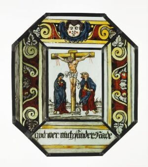  An octagonal stained glass panel featuring the Crucifixion of Jesus with Mary and Saint John in the central scene, surrounded by decorative scrollwork and heraldic symbols in a palette of red, blue, green, yellow, and white.