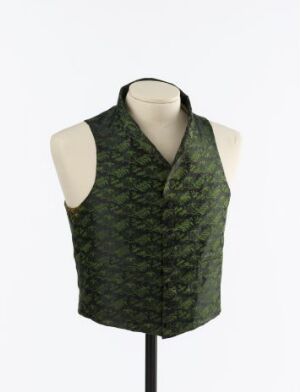  A sleeveless, handwoven silk vest known as Syttende Mai Veste by an unidentified artist, displayed on a mannequin. The vest has dark and light green patterns, a V-neck, and a cotton lining. It is a traditional piece, likely worn for formal events or celebrations.