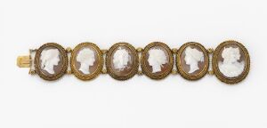  A vintage-style bracelet composed of seven gold-tone oval frames linked together, each containing a white cameo silhouette against a light background, with intricate profiles displayed in each frame.