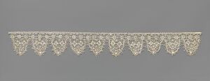  An ornate, white lace border with scalloped edges and intricate floral motifs set against a gray background.