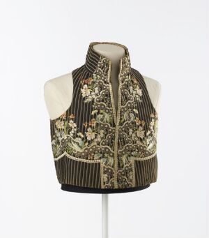  A mannequin torso displaying a richly patterned vest with floral designs in olive green, brown, and cream, featuring a high ribbed collar and striped hem.