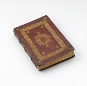  An antique, dark maroon hardcover book with gold embossed detailing on the cover, showing signs of wear, against a light gray background.