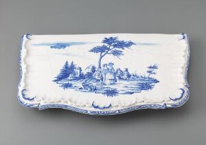  A rectangular white-glazed faience platter titled "Bordplate" by an unidentified artist, featuring intricately hand-painted blue decorations displaying a central tree and surrounding landscape with figures, showcasing traditional faience design elements against a white backdrop.