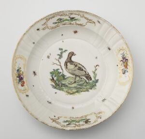  A porcelain plate from Den kgl. Porcelainsfabrik with scalloped edges, featuring an intricately painted duck surrounded by flora, insects, and butterflies in a variety of colors on an off-white background.