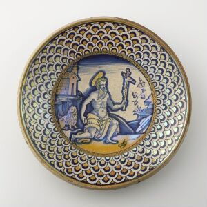  A circular plate with a decorative scale-like rim pattern transitioning from yellow to blue, featuring a central painted medallion with a white-clad figure, an owl, stars, and a classical column, suggesting a mythological theme.