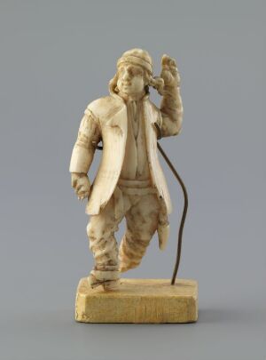  A carved walrus ivory figurine called "Mann fra Fana" by artist Jørgen Christensen Garnaas, depicting a man in traditional clothing with his hand to his ear, on a rectangular base, featuring intricate detail and a natural creamy ivory color with light brown accents, and a secondary metal support rod attached to the back of the figure.