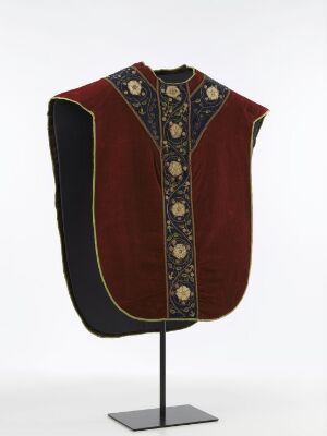  A traditional dark maroon velvet vest with golden floral embroidery and black silk edging on a mannequin stand against a grey background.