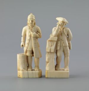  Two carved ivory figurines by Jørgen Christensen Garnås, titled "To figuriner," depict 18th-century European gentlemen with detailed period costumes, standing side by side against a plain background, each on a small ivory base.