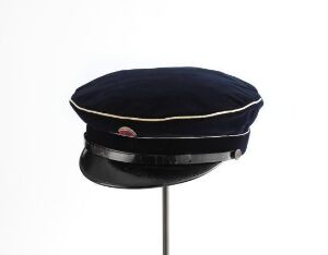  A traditional navy blue velvet "russelue" student cap designed by Hans H Holm a/s, featuring a glossy black lacquered brim and a gold band circling the base, displayed on a stand against a white background.