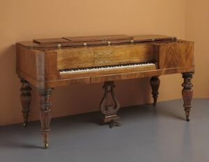  An antique square grand piano made of burled wood with elaborate legs, set against a simple beige background. The lid is open, exposing the strings and piano hammers, with the visible keyboard suggesting readiness for a musical performance.