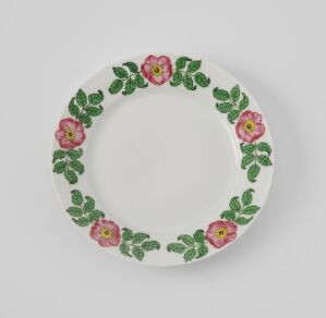  Porcelain plate from Porsgrunds Porselænsfabrik AS's "Dekor 2838" collection, featuring a shiny white background with a border of hand-painted flowers in deep and light pink, surrounded by dark green leaves, creating a vibrant decorative pattern around the rim.