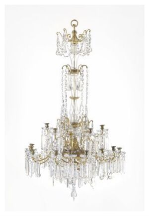  An opulent gold and crystal chandelier with multiple tiers and candle-like bulb holders against a neutral light background.