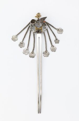  A decorative hairpin with a long metallic shaft and a radiant ornate top embellished with sparkling stones and colored gems, designed to look like a stylized sunburst or firework, set against a plain background.