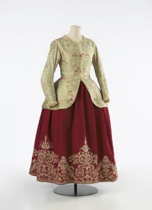  An 18th-century style costume on a mannequin, featuring a pale green embroidered jacket and a rich maroon bell-shaped skirt with golden embroidery.