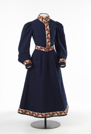  A vintage navy blue full-length dress with intricate red, orange, and gold patterned trim on the neckline, waist, and sleeve cuffs, displayed on a mannequin against a neutral background.