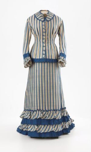  Historical ankle-length striped dress with long sleeves, high neckline, dark blue waistband, and tiered ruffled hem in shades of cream and dusty blue, set against a plain light background.