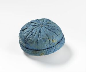  A well-worn, vintage-style fabric cap in faded blue with subtle yellow accents, showcasing a detailed texture and segmented pattern, on a light grey background.