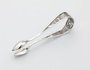  A pair of ornate silver sugar tongs with intricate cut-out patterns on the handles, set against a light gray background.