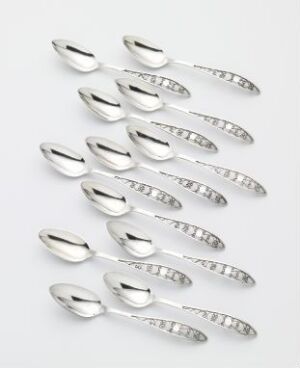  Twelve identical silver spoons with ribbed handles arranged in three columns and four rows on a subtle grey background, showcasing their reflective, polished surfaces.