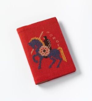  Red cotton book cover featuring hand-embroidered cross-stitch and Holbein stitch design of a dark blue horse with a multi-colored mane and tail, and the word "NORGE" in yellow above it, designed by Else Poulsson.