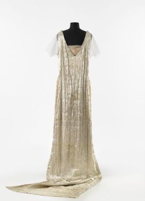  A vintage floor-length gold dress with a subtle train and sheer cap sleeves, adorned with vertical beading, displayed on a torso-only mannequin against an off-white background.