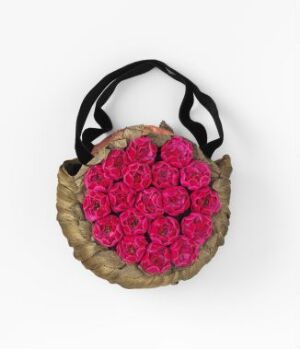  A hand-woven, beige-colored basket hung by a black strap and filled with a cluster of vibrant pink roses against a neutral light grey background. The basket has a rustic texture, and the roses range in shades of fuchsia to light pink.