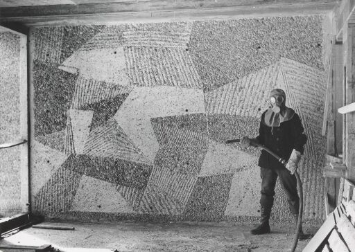 Carl Nesjar under sandblåsing av et monumentalverk i trappehuset